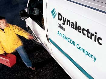 Worker carrying a red toolbox walking toward a service van labeled ‘Dynalectric Ohio – An EMCOR Company.’