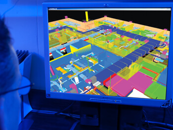 “Engineer viewing a 3D building model with mechanical and electrical systems displayed on a computer monitor.